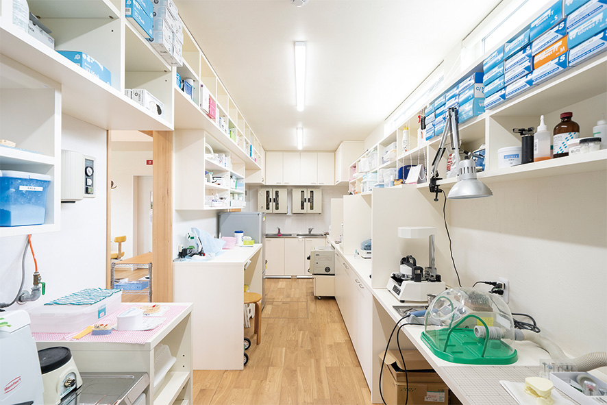 <p>歯科技工のスペースは、漆喰の白で統一した清潔感あふれる空間。壁面棚を設け、薬品や備品などを収納。コンパクトな広さながら、作業スペースをしっかり確保している。</p>
